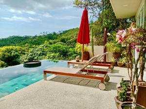 a pool with two lounge chairs and a red umbrella at Luxury Asian Flair Villa in Koh Phangan