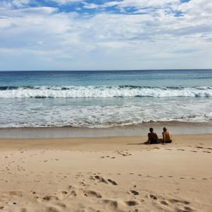 Due persone sedute sulla spiaggia a guardare l'oceano di Casa Majahualt a San Juan del Sur