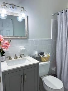 ein Badezimmer mit Waschbecken, Toilette und Spiegel in der Unterkunft Rockstar Hideaway Entire Home 2BR 2BA Office Space Guest Room & Outdoor Patio in Hollywood