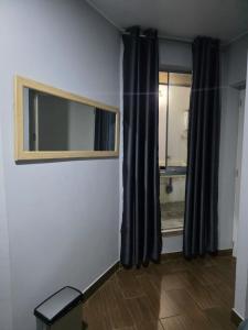 Una habitación con una ventana con cortinas negras y un espejo. en Casa sabina nuevo aeropuerto, en Lima