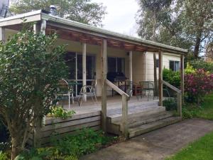 a cottage with a porch with a table and chairs at Ohuka Lodge in Tuai +51 photos