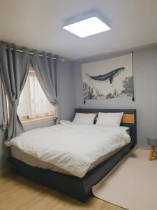a bedroom with a bed with a whale painting on the wall at Stay Ali in Gyeongju