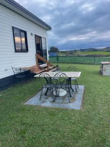 a patio with a table and chairs in the grass at Boutique Tiny House Stargazing & Rural Views in Parore +18 photos