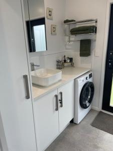 a bathroom with a sink and a washing machine at Boutique Tiny House Stargazing & Rural Views in Parore