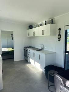 a kitchen with white cabinets and a sink and a bed at Boutique Tiny House Stargazing & Rural Views in Parore