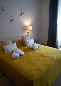 um quarto com uma cama amarela com toalhas em O Forte Guest House em Peniche