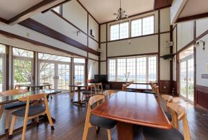 a large room with tables and chairs and windows at Pension Sora in Nachikatsuura