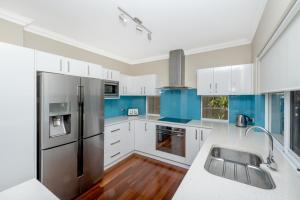 eine Küche mit weißen Schränken und blauen Akzenten in der Unterkunft EAST3 - Coastal Hideaway in Mosman Park
