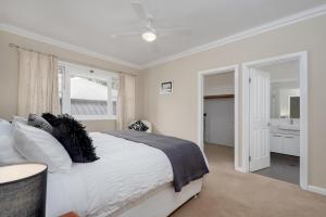 ein weißes Schlafzimmer mit einem Bett und einem Badezimmer in der Unterkunft EAST3 - Coastal Hideaway in Mosman Park
