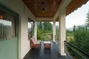 a porch with two chairs and a table and a door at Tranquil House Manali in Haripūr