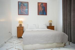 ein Schlafzimmer mit einem weißen Bett und zwei Gemälden an der Wand in der Unterkunft Clarah's paradise in Mombasa