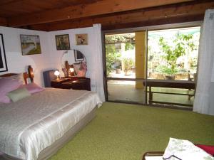a bedroom with a bed and a large sliding glass door at Shady Grove B&B in Hervey Bay