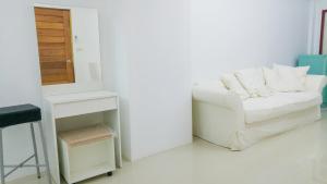 a white couch sitting in a room with a mirror at Studio in townhouse with private bath room and kitchenette in Amphoe Phra Khanong