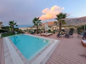 a large swimming pool with palm trees and a mountain at Hela Residence in Orikum