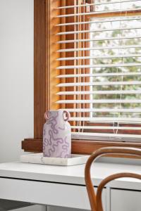 un vase violet posé sur un rebord de fenêtre dans l'établissement Charming 1930s Cottage Retreat I Pet Friendly Escape, à Geelong West 21 autres photos