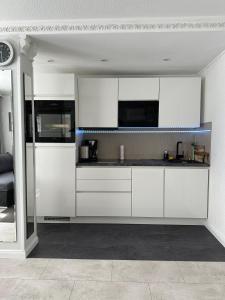 a white kitchen with white cabinets and appliances at Ruhige geräumige Wohnung in Pforzheim