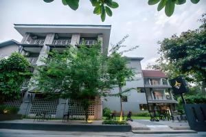 a building with a tree in front of it at Sabaidee Chiangmai Hotel in Chiang Mai