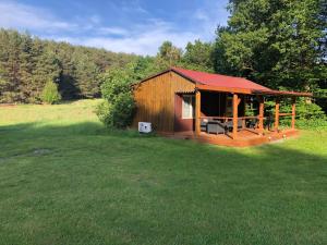 a small cabin with a red roof in a field at Siedlisko Silna Nowa in Silna Nowa