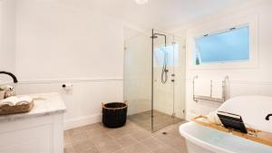 a white bathroom with a shower and a sink at Glenbrae in Bundanoon