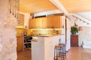 a kitchen with wooden cabinets and a bar with two stools at Casa artística i acollidora a Pau in Pau