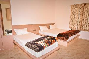 une chambre avec deux lits et un miroir dans l'établissement Hotel Rudraksha Restaurant And Resort, à Khātu