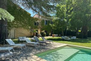 un gruppo di sedie e una piscina di fronte a una casa di The Grand Mas Domaine du Moulin de Perdrix a Mudaison