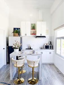 Boutique Studio in Laoag City في Sagneb: مطبخ مع خزائن بيضاء و كراسي من البار الذهبي