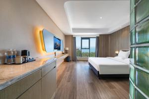 威海World Hotel Weihai International Bathing Beach Torch 8th Street Branch的配有床和电视的酒店房间