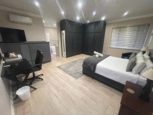 a bedroom with a bed and a desk and a computer at Grants Hill Inn in Bloemfontein