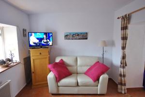 a living room with a white chair and a television at Apartament Casa Levante in Vejer de la Frontera