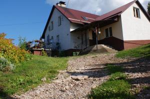 a white house with a red roof on a hill at Agroturystyka Pod Rumakiem in Chęciny
