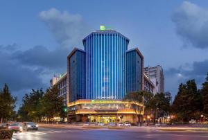 a large building with blue windows on a city street at Holiday Inn Express Yangzhou City Center By IHG in Yangzhou