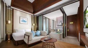 a room with a bed and a couch and a table at Fliport Hotel Zhangzhou Yuanshan in Zhangzhou