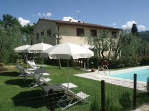 einen Pool mit Stühlen und Sonnenschirmen neben einem Haus in der Unterkunft Agriturismo IL VIAIO in Fiesole