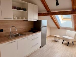 a kitchen with white cabinets and a stainless steel refrigerator at Atpūta Grašos Mazirbe in Mazirbe