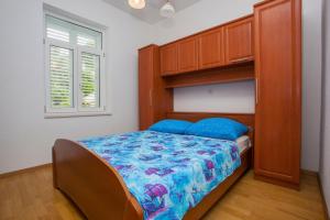 a bedroom with a bed and a wooden cabinet at Apartments Sumic Podgora in Podgora
