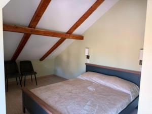a bedroom with a bed and two chairs at Atpūta Grašos Mazirbe in Mazirbe