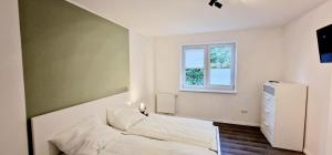 a bedroom with a white bed and a window at Ferienhaus Strandallee 10 in Burhave