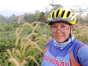 a woman wearing a bicycle helmet standing in a field at Moonshadow in Sungai Kolok