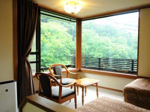 a room with two chairs and a table and a window at Hotel Nanpuso in Hakone