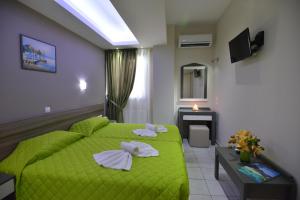 um quarto com uma cama verde e uma televisão em Vesperi Studios & Apartments em Rethymno Town