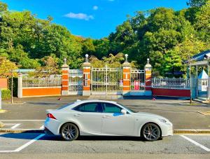 a white car parked in a parking lot next to a gate at ヴィラ犬山 in Inuyama