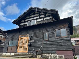 una casa nera con una porta arancione di 笑庵emian a Hakusan