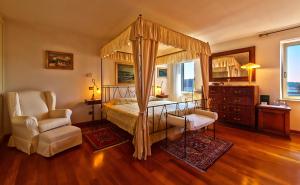 ein Schlafzimmer mit Himmelbett und Sessel in der Unterkunft Villa Tuttorotto in Rovinj