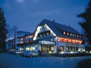 a large building with cars parked in a parking lot at Schwarzwaldhotel Oberwiesenhof in Seewald