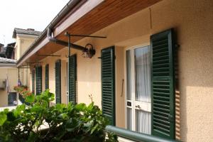 a group of green shutters on a building with a window at Hotel Centro in Torre Pellice