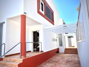a white house with red columns and a staircase at Lunamar in San José