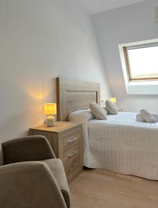 a bedroom with two beds and a chair and a window at Airtegal Atico Mar de Cedeira in Cedeira