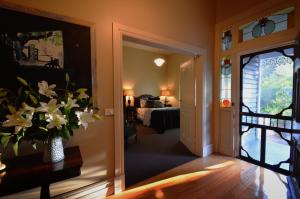 un pasillo con una habitación con cama y un jarrón de flores en Clement House, en Benalla