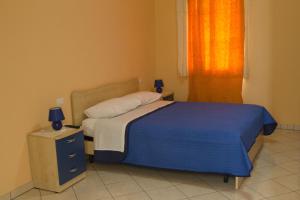 una camera da letto con un letto con una coperta blu e una finestra di B&B L'Angolo a Sannicola